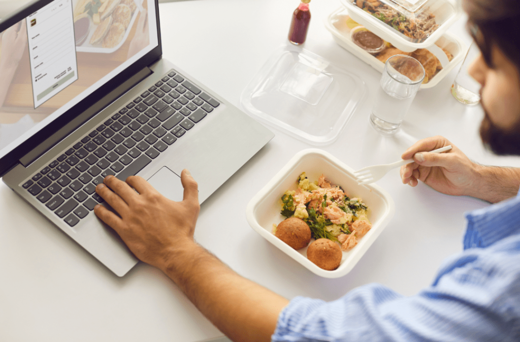 man eating and working on laptop