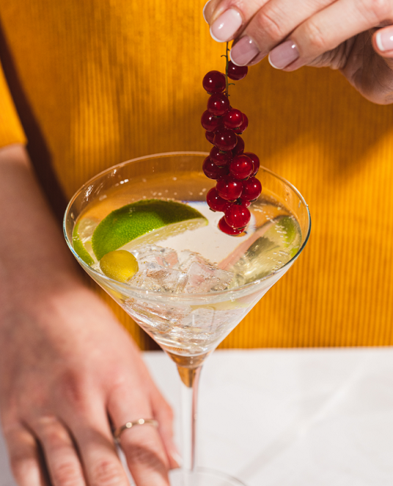 Woman adding berries to a lemon drink