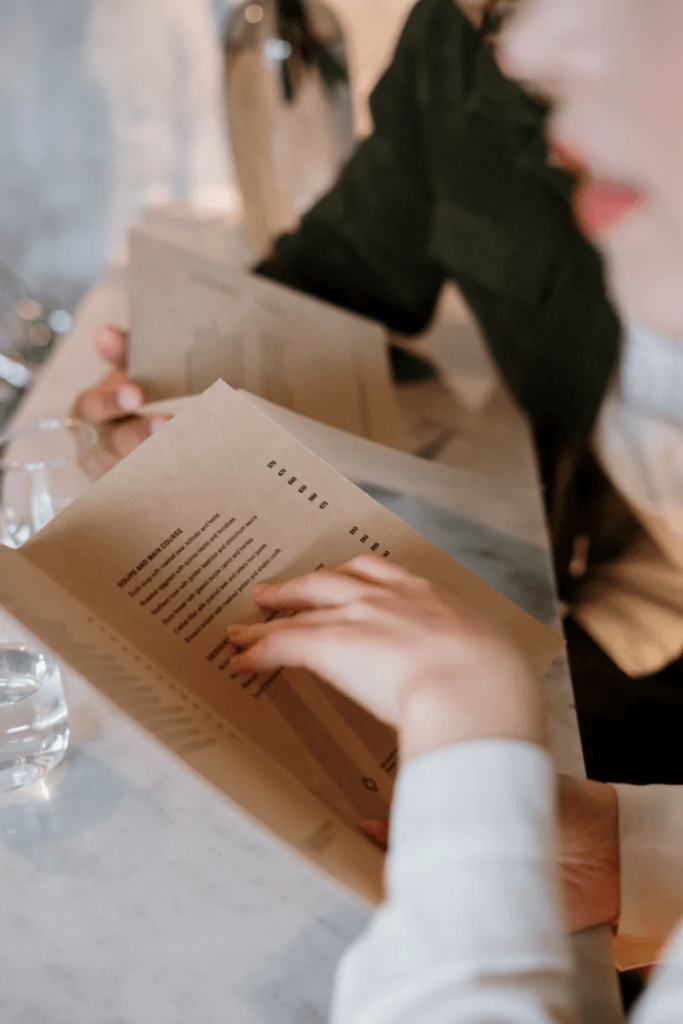 A woman engrossed in reading a menu at a restaurant