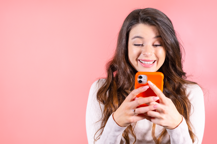 A lady smiling while reading something on her phone