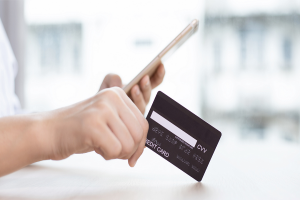 A person holding a credit card and a phone