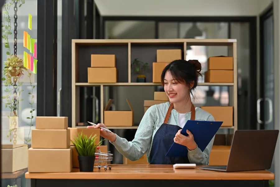 A lady reviewing the packed boxes with a laptop in front of her